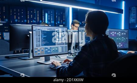 Smart Female IT Programer Working on Desktop Computer in Data Center System Control Room. Team of Young Professionals Doing Code Programming Stock Photo
