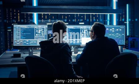 Two Professional IT Programers Discussing Blockchain Data Network Architecture Design and Development Shown on Desktop Computer Display. Working Data Stock Photo