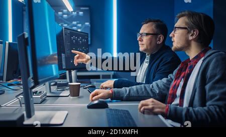 Two Professional IT Programers Discussing Blockchain Data Network Architecture Design and Development Shown on Desktop Computer Display. Working Data Stock Photo