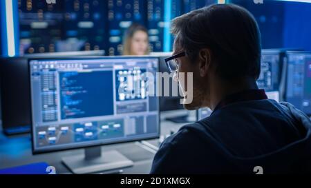 Smart Male IT Programer Working on Desktop Computer in Data Center Technical System Control Room. Team of Young Professionals Programming in Coding Stock Photo
