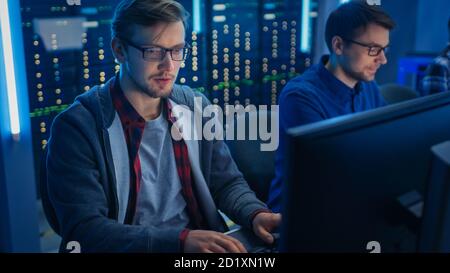 Team of Young IT Programers Working on Desktop Computers in Data Center System Control Room. Displays Show Concept: Software Development Code Writing Stock Photo
