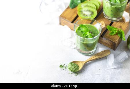 Detox green smoothie - kiwi, spinach and matcha on a light grey slate, stone or concrete background. Stock Photo