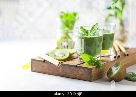Detox green smoothie - kiwi, spinach and matcha on a light grey slate, stone or concrete background. Stock Photo