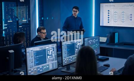 Team of Professional IT Developers Have a Meeting, Speaker Talks about New Blockchain Based Software Development Shown on TV. Concept: Deep Learning Stock Photo