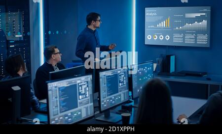 Team of Professional IT Developers Have a Meeting, Speaker Shows Growth Data with Graphs, Charts, Software UI. Shown on TV. Concept: Software UI Stock Photo