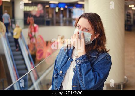 Woman with fear puts on medical mask in shopping mall. Trouble in store with coronavirus pandemic and shoppers Stock Photo