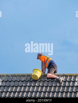 Working on a pitched roof without safety gear. Stock Photo
