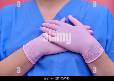 A doctor in medical gloves puts his hands to the heart. The concept of ending the coronavirus epidemic and removing quarantine. Stay home Stock Photo