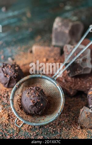 Delicious Chocolate truffles with cocoa powder and dark chocolate on a dark wooden background. Stock Photo