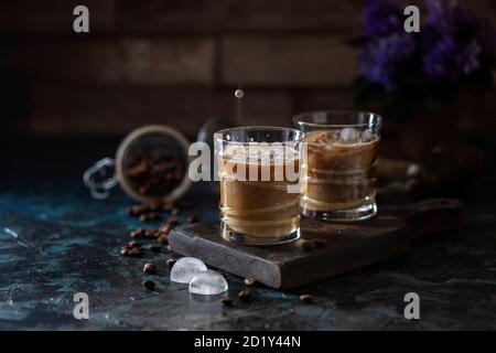 Ice coffee espresso a glasses, with milk, being poured over from pitcher by hand. Summer refreshing beverage. Stock Photo