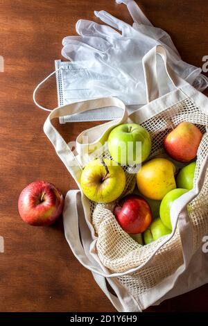 Eco mesh bag with apples supplies on a wooden background. Food delivery in eco-friendly packaging, zero waste. Stock Photo