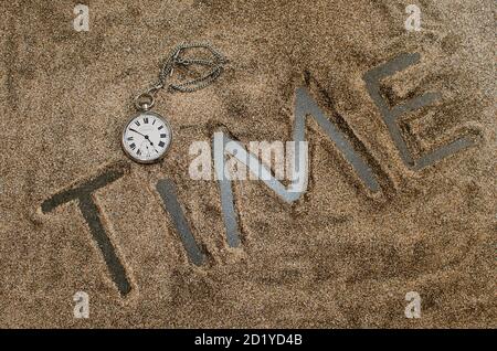 Old pocket watch placed on the word time. Time letters in Black. Roman nos indicating time Stock Photo