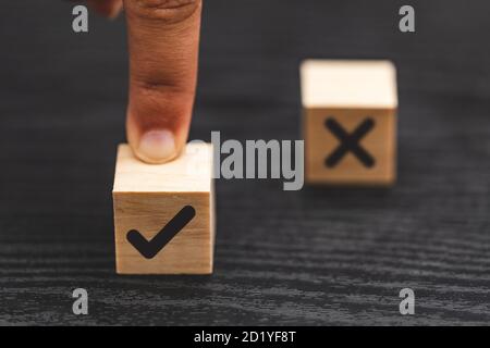 hand choose yes, true and blurred NO, false symbols on wood cube - True and false symbols accept rejected for evaluation Stock Photo