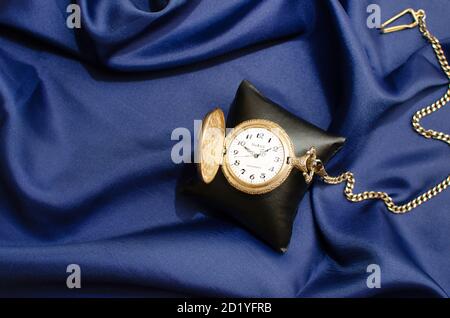Old fashioned pocket watch with chain. Navy Blue Background. Studio Shot Stock Photo