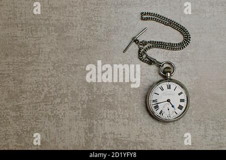 Old fashioned pocket watch with chain.  Roman numbers indicating time. Grey Background. Studio Shot Stock Photo
