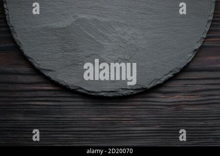 round black slate board on dark wooden table Stock Photo