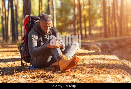 Black guy injured his leg during travel in forest Stock Photo