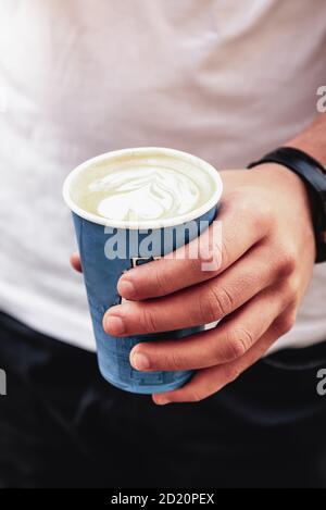 Young Man Holding Coffee Disposable Paper Cup in Street Stock Photo