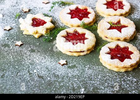 Christmas or New Year tree made from Austrian Linzer cookies with jam and dusted with sugar powder on green stone background. Holiday, celebration and Stock Photo