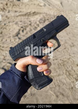 Police gun in a woman's hand. Stock Photo