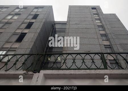 A dull gray building from the old days. Retro building was constructed for production or industry. Grey skies over the sad city landscape. Stock Photo