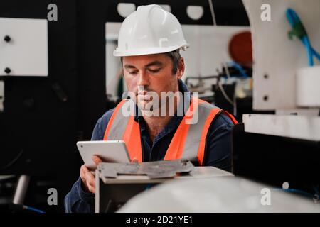 Male engineer researching on digital tablet in factory. Stock Photo