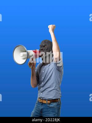 Man in gorilla mask protesting on megaphone. Isolated cutout on blue background. Medium shot. Side view. Stock Photo