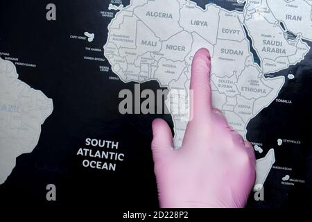The hand of a nurse in a protective glove on the world map shows Africa. Concept of the coronavirus epidemic in the countries of the African continent Stock Photo
