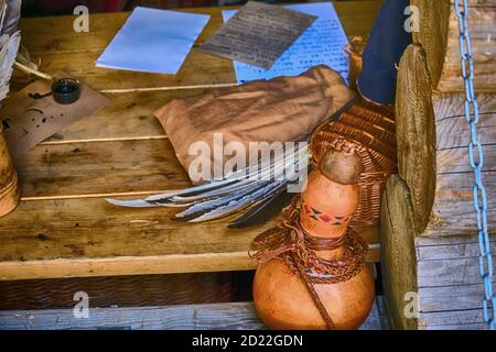 Feathers, ink and paper in a wooden house. Table with writing utensils in retro style. Stock Photo