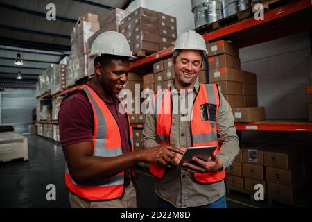 Smiling workers browsing on digital tablet watching funny videos standing in factory  Stock Photo
