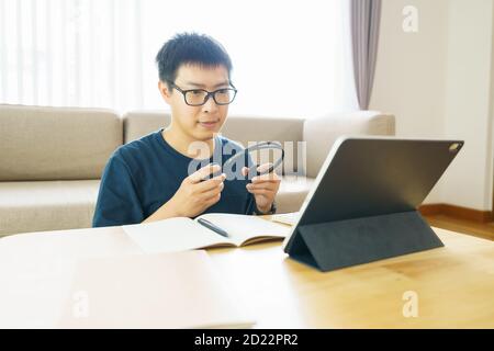 Asian man aged 30-40 years using tablet, watching lesson online course communicate by conference video call from home, e-learning education concept Stock Photo