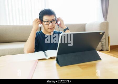 Asian man aged 30-40 years using tablet, watching lesson online course communicate by conference video call from home, e-learning education concept Stock Photo