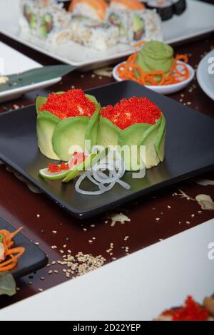 close view of tobiko avocado served in black plate on wooden table. Selective focus. Stock Photo