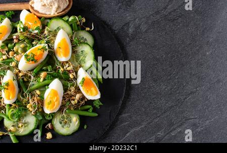 healthy low carb salad with green vegetables and eggs on dark background with copy space Stock Photo