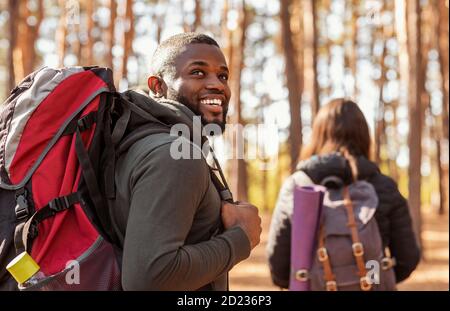 Happy black guy looking aside, hiking with girlfriend Stock Photo