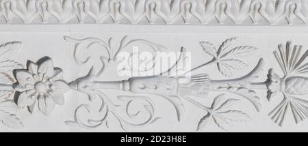 A white floral plaster relief on a white plastered wall. Elements ornament for use as a texture or background Stock Photo