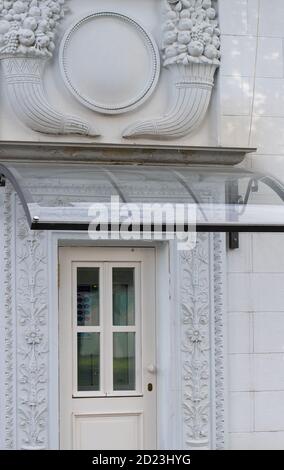 A white floral plaster relief on a white plastered wall, bas-relief with stucco mouldings roccoco element. Stock Photo