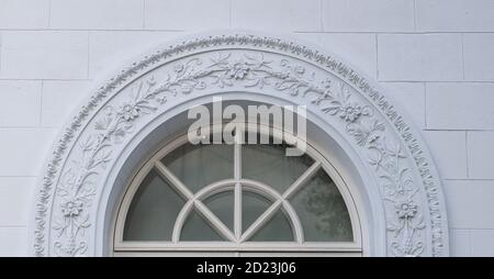 A white floral plaster relief on a white plastered wall. Elements ornament for use as a texture or background Stock Photo