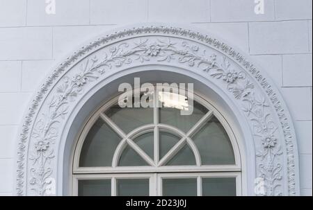 A white floral plaster relief on a white plastered wall. Elements ornament for use as a texture or background Stock Photo