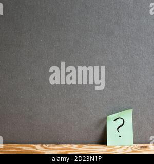 Sticky memo note paper with question mark on the gray wall. Thinking, solution, business, idea concept Stock Photo