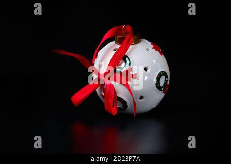 White bauble sphere with red ribbon decorated with Christmas wreath on black. New Year tree decoration Stock Photo