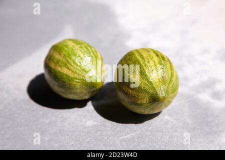 Two whole striped lemons, Variegated pink lemons or pink-fleshed Eureka lemons on gray concrete table. Citrus fruits Stock Photo