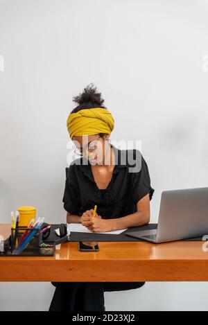 Shot of young latin woman working at home office with laptop and documents Stock Photo