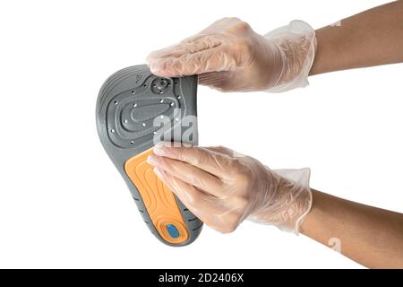 Orthopedist holds the insoles in his hands on white background, close-up. Only hands , on hygienic gloves. Stock Photo