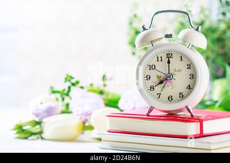 Retro alarm clock, notebook and spring flowers. Stock Photo