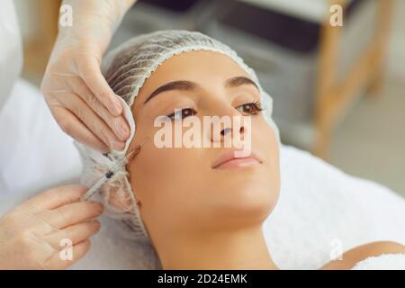 Thherapist making facial beauty botox injection for young womans cheek to stop aging Stock Photo