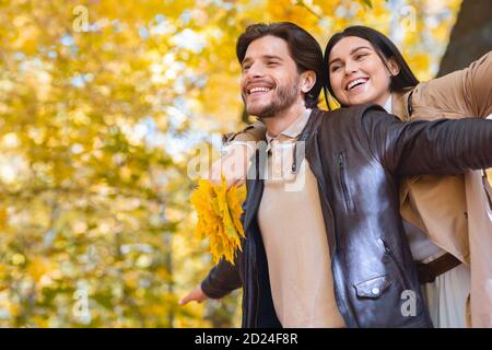 Carefree lovers imitating flying on golden forest background Stock Photo