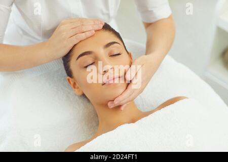 Close-up of serene woman getting procedure of relaxing manual facial massage from masseur Stock Photo