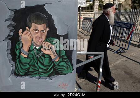 A pedestrian walks past a painting, depicting captured Israeli soldier Gilad Shalit, hung outside a protest tent calling for his release, near the residence of Israeli Prime Minister Benjamin Netanyahu in Jerusalem July 7, 2009. Egyptian President Hosni Mubarak said on Tuesday he believed the Israeli soldier captured by Palestinian militants three years ago was well and that he hoped the issue would not take a long time to resolve. REUTERS/Baz Ratner (JERUSALEM POLITICS CONFLICT IMAGES OF THE DAY)