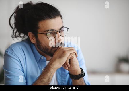 Closeup Portrait Of Pensive Millennial Indian Man In Eyeglasses Looking Away Stock Photo